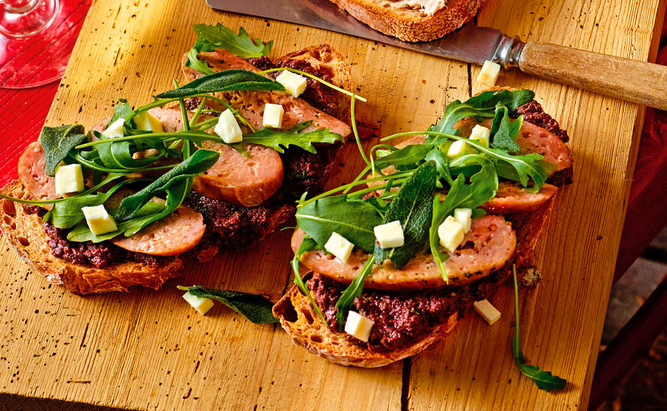 Brot mit Olivenpesto, Salsiccia, Mozzarella und Rucola